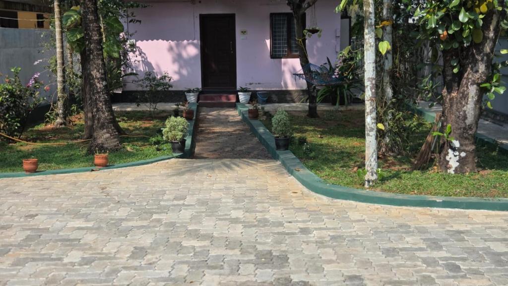 a walkway in front of a house with trees at White Sands Cottage in Alleppey