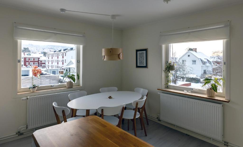 a dining room with a table and two windows at Lugnt läge i centrala Rättvik in Rättvik