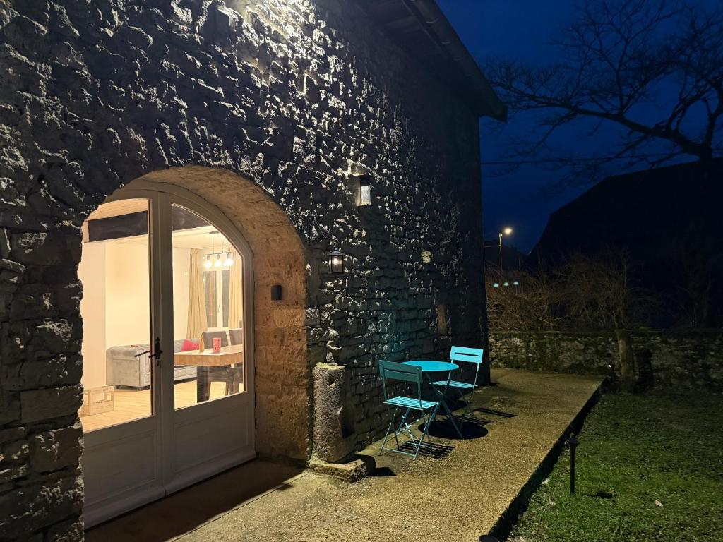 a door to a stone building with a table and a bench at Gîte 2 suites proche du lac de Chalain in Montigny-sur-lʼAin