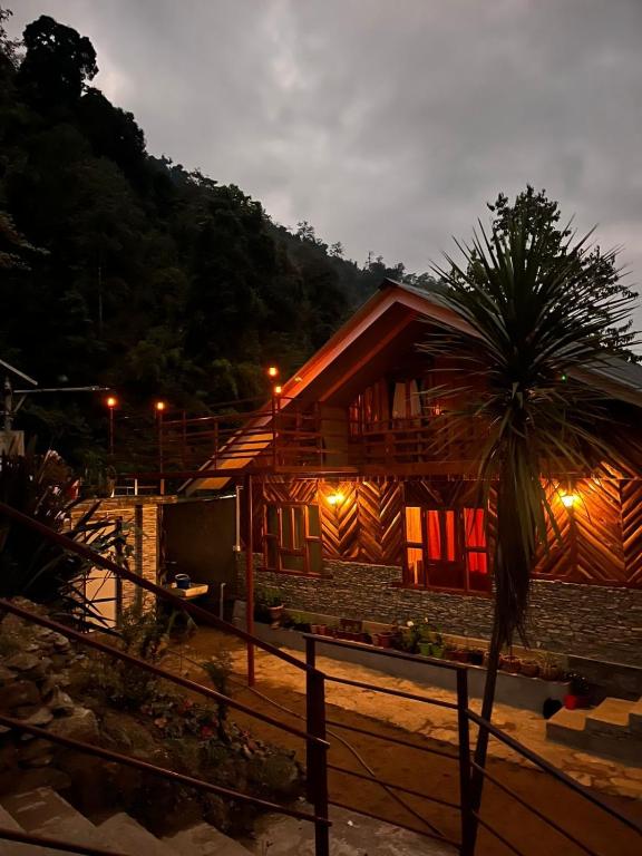 a wooden house with a palm tree in front of it at Tamu Kyi Retreat in Kaluk