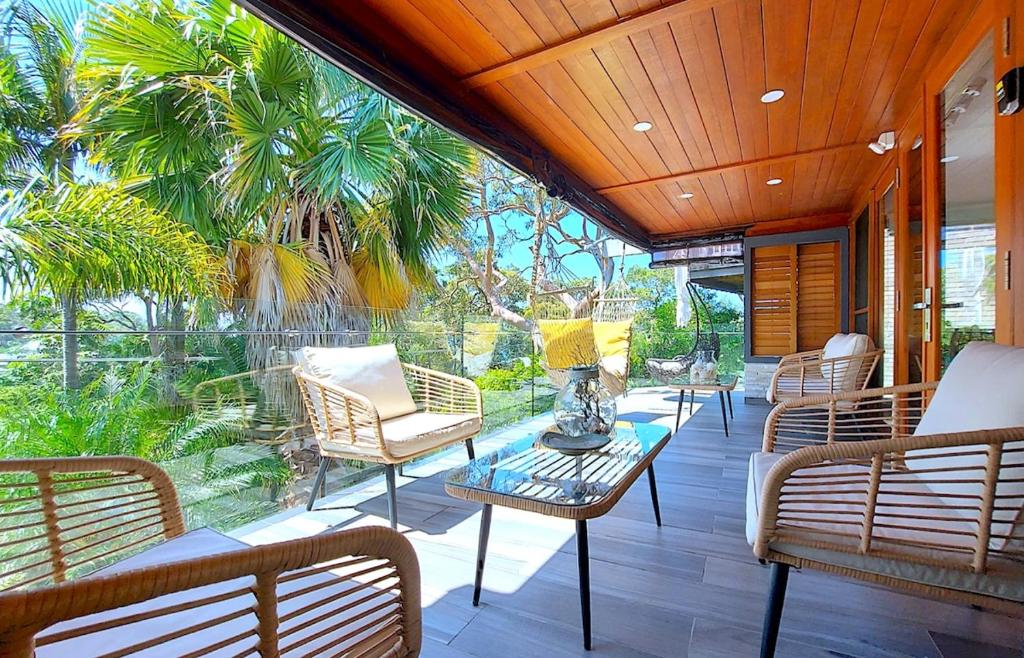 a porch with wicker chairs and a glass table at PALMIE Gold in Palm Beach