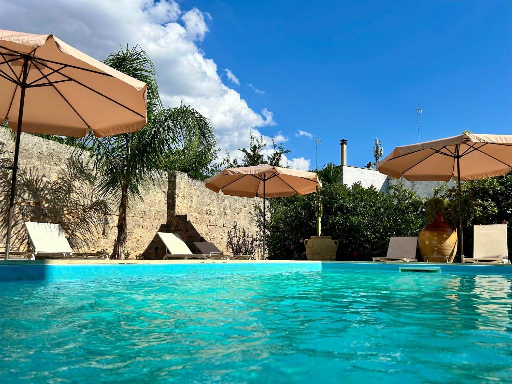 a swimming pool with two umbrellas and chairs at B&B Don Alessandro in Surbo