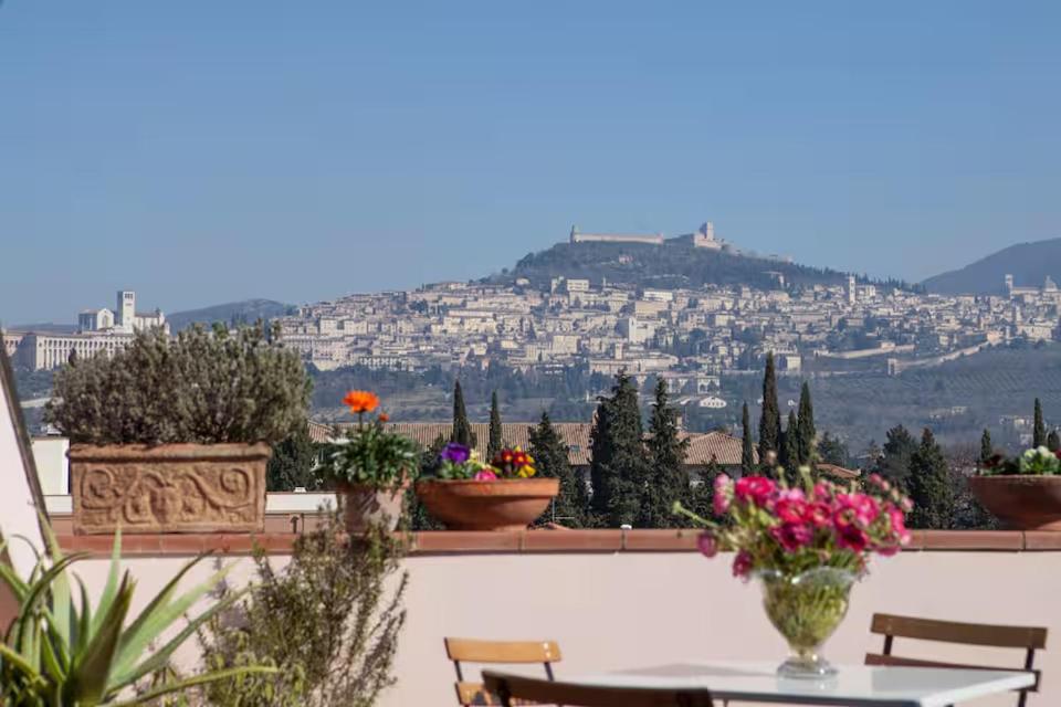 a view of a city from a balcony with a table and flowers at L'Attico Affittacamere in Santa Maria degli Angeli