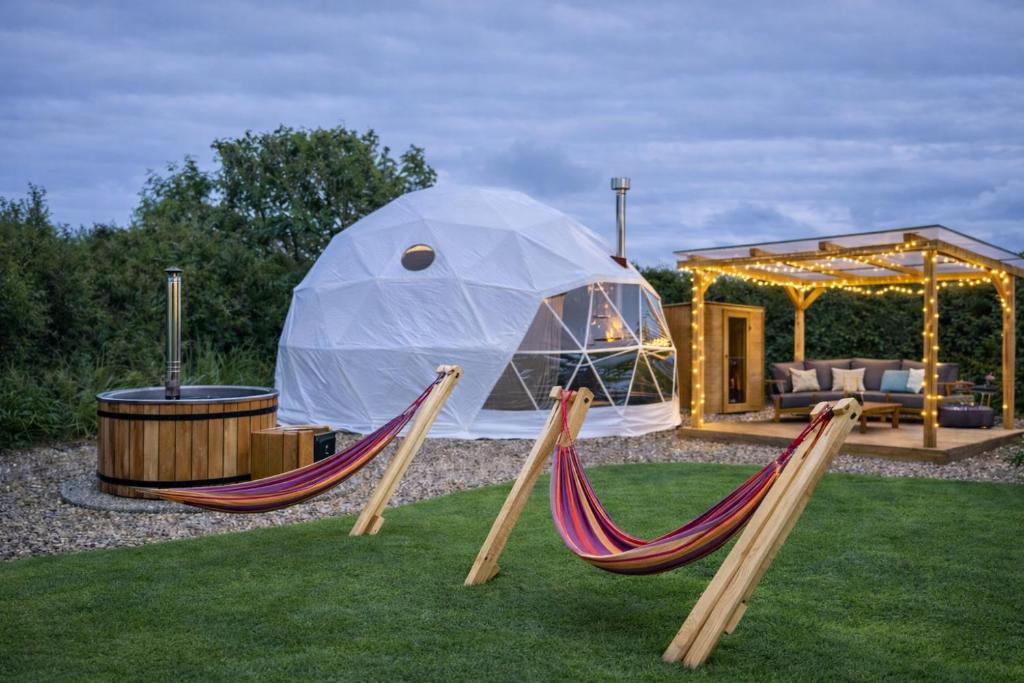 two hammocks in a yard with a tent at Grass Roots Retreat in Llanstadwell