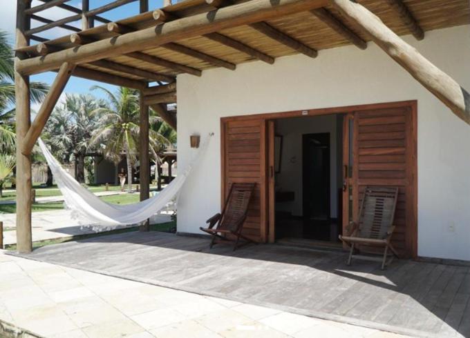 two chairs and a hammock outside of a house at Hotel Vila Marola in Taíba
