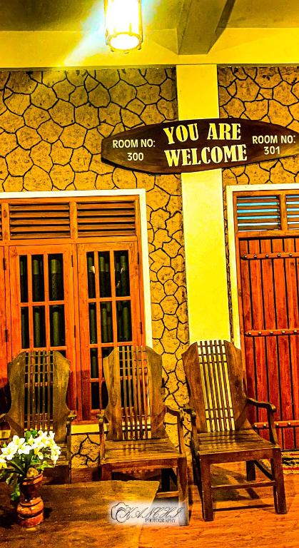 two chairs and a sign in front of a building at Kanchi's please in Udawalawe