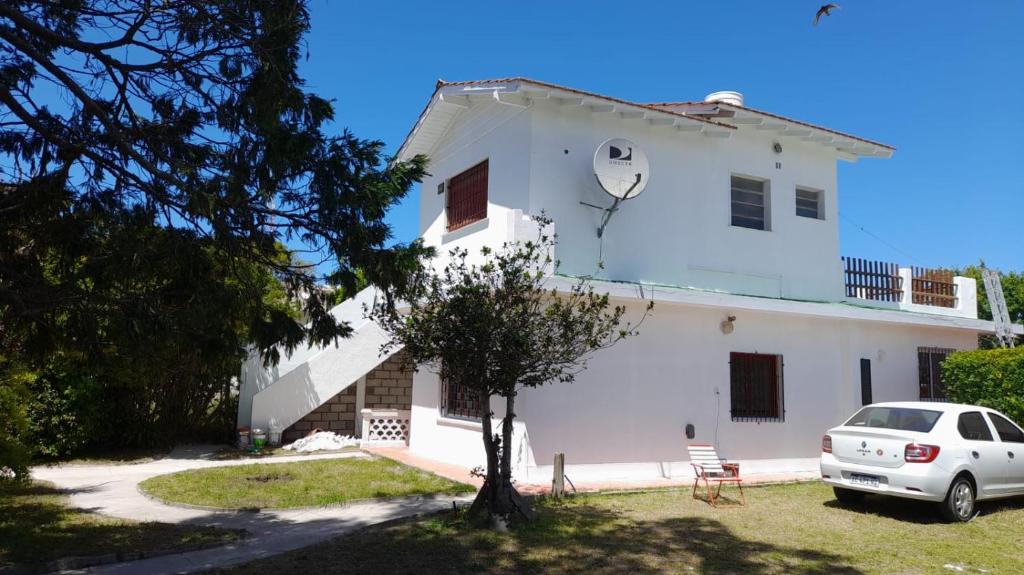 a white house with a car parked in front of it at Casa 7 personas in Villa Gesell