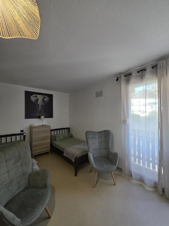 a living room with a bed and two chairs and a window at Appartement BARBOTAN LES THERMES in Cazaubon