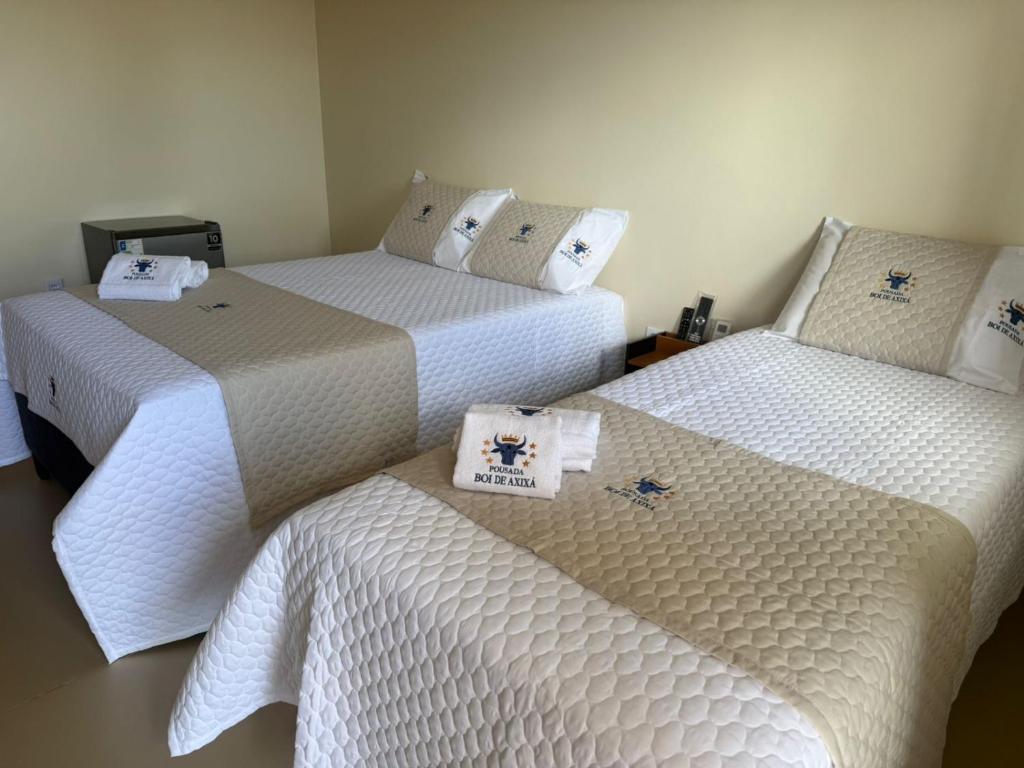 three beds in a room with white sheets at Pousada Boi de Axixá in Barreirinhas