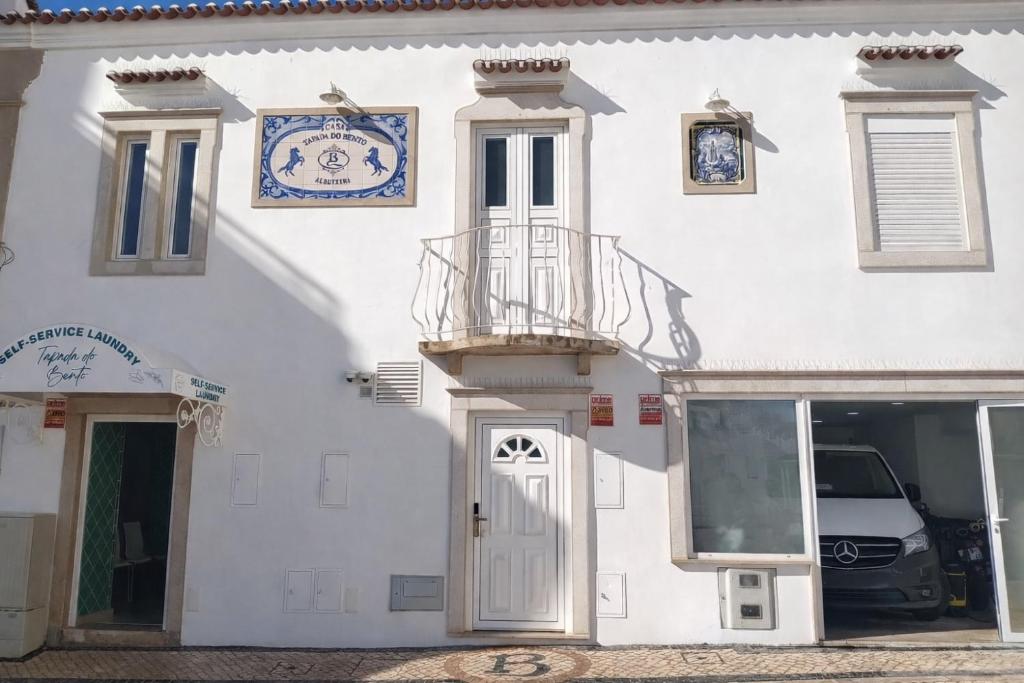 a white building with a clock on the side of it at Casa Tapada do Bento II- Albufeira in Albufeira