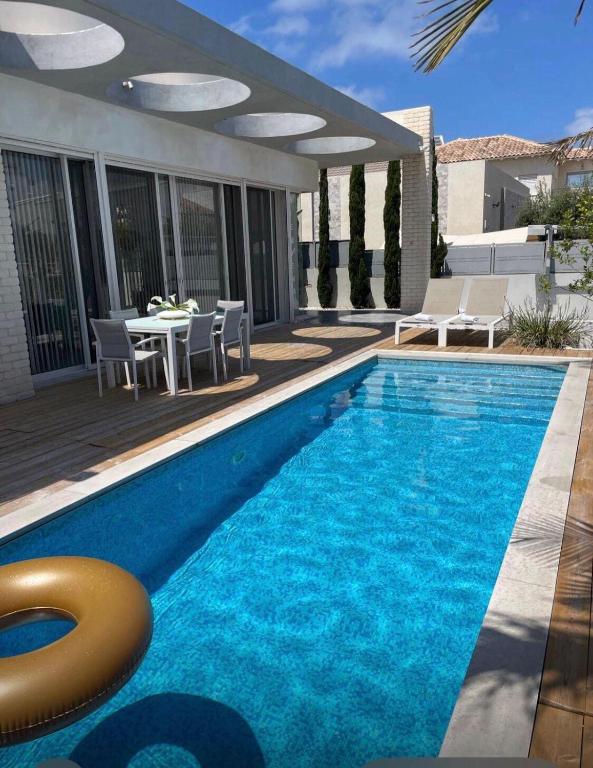 a pool with a table and chairs next to a house at Apartment with private pool in Ashkelon