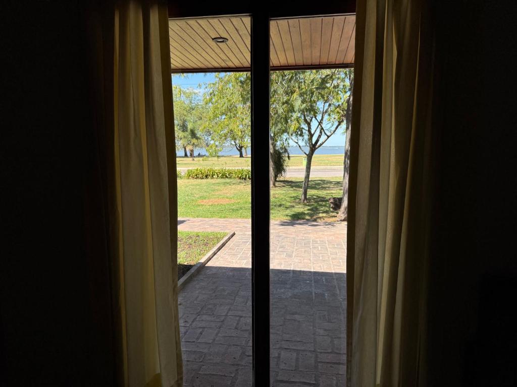 an open glass door with a view of a yard at Costanera 61, frente a la laguna in Chascomús