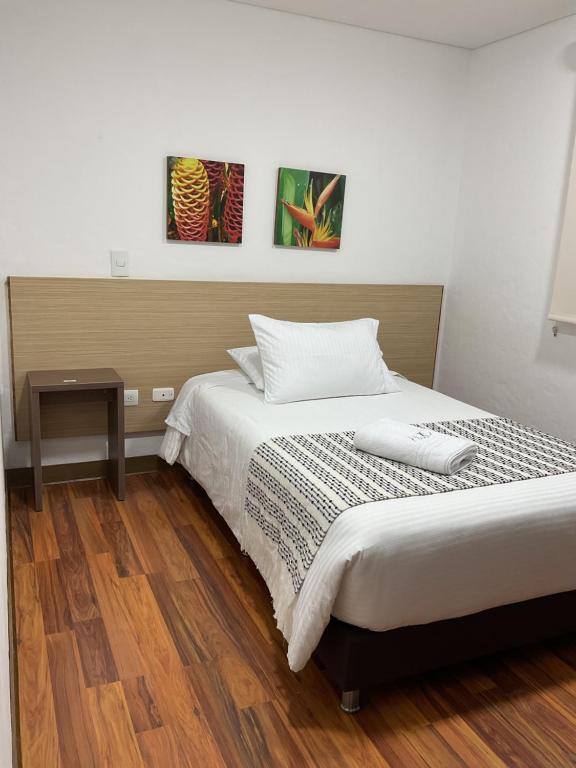 a bedroom with a bed and a table and two paintings at Hotel Quinta del Café in Fredonia