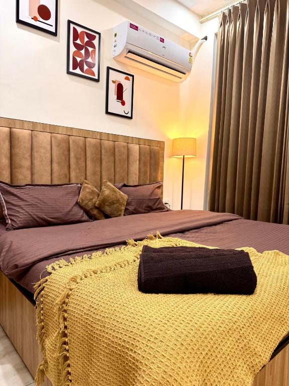 a bedroom with a bed with a yellow blanket on it at Luxe Label Studio by Sam in Zirakpur