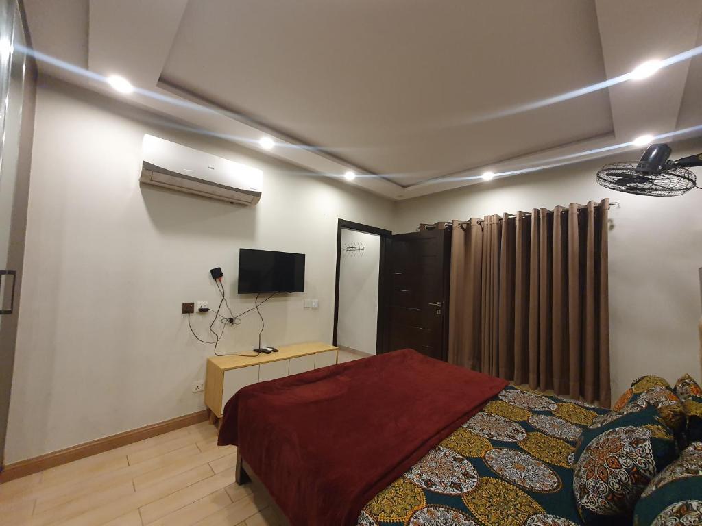 a bedroom with a bed and a tv on the wall at Sunset heaven in Lahore