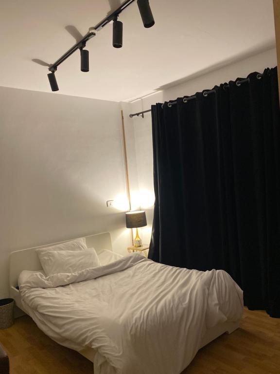 a bedroom with a white bed with a black curtain at Clouds chase in Madinaty