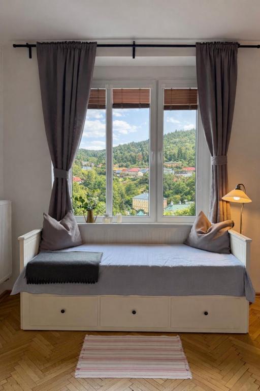 a bed in a room with a large window at Panoráma apartmán Centrum in Banská Štiavnica