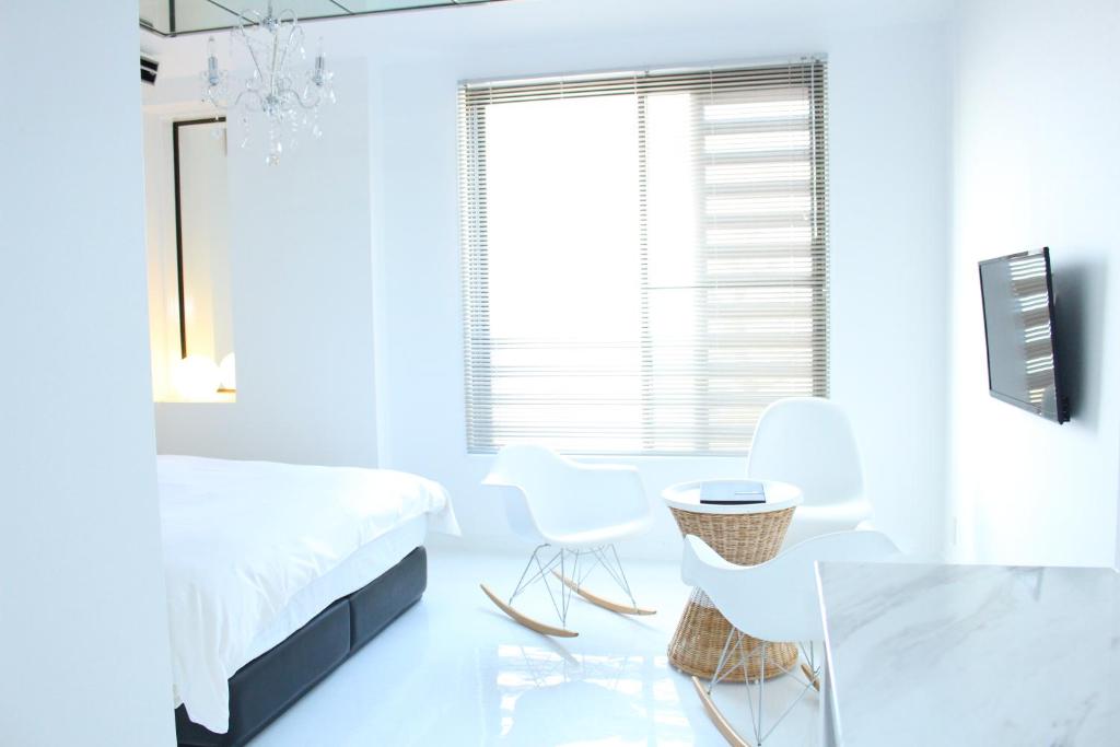 Sea Style Resort OCEAN في كاراتسو: غرفة نوم بيضاء بسرير وطاولة وكراسي