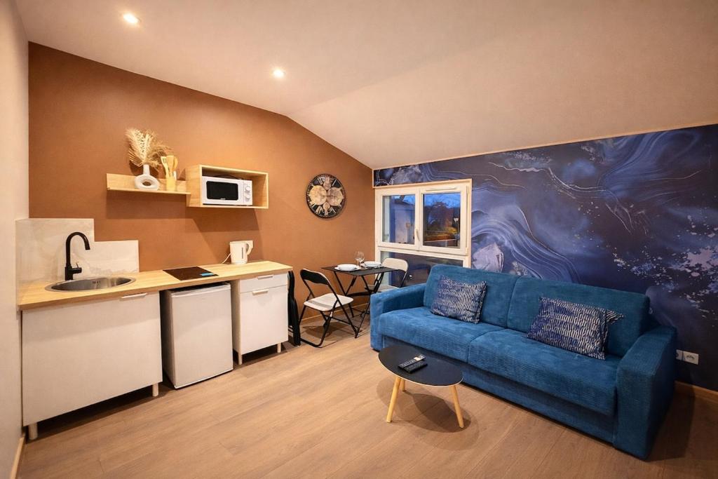 a living room with a blue couch and a kitchen at Le Saphir avec Parking gratuit in Montigny-le-Bretonneux