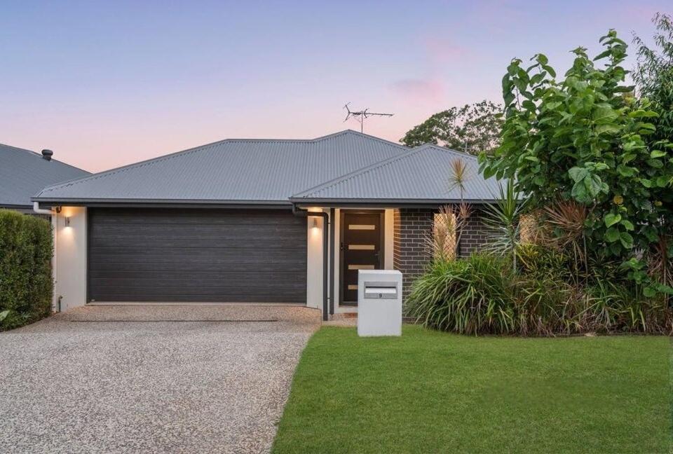 a house with a garage in a yard at JOT Luxe Haven in Narangba