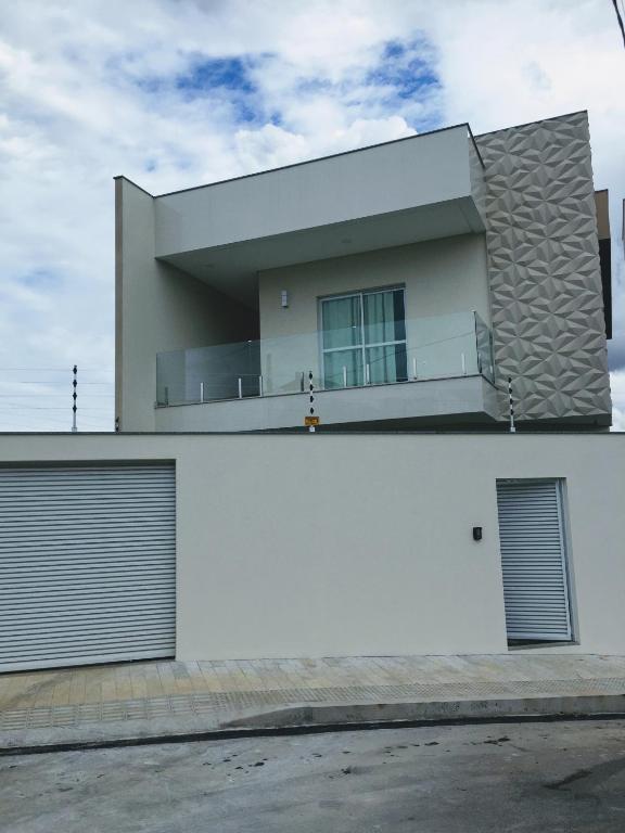 a white house with two garage doors at Quarto próx a Praia do Morro in Guarapari