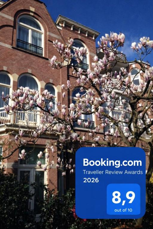 a tree with pink flowers in front of a building at Flora's Palace - The Hague Scheveningen in The Hague