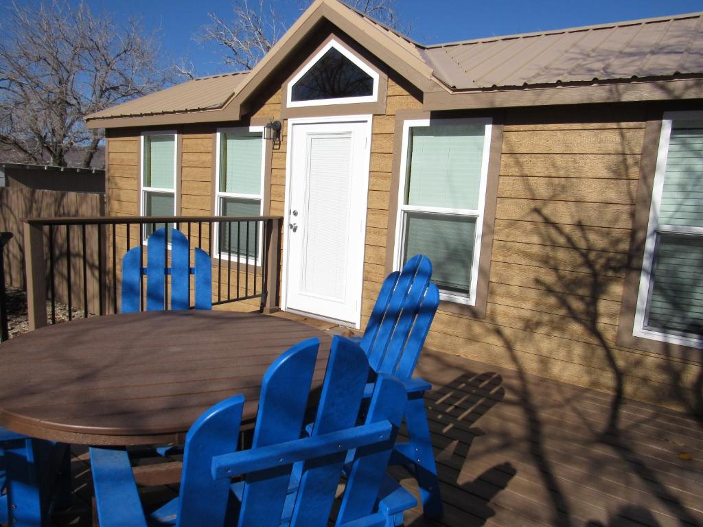 two blue chairs and a wooden table in front of a house at Kingman KOA in Kingman