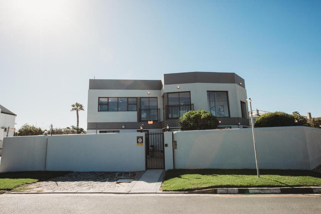 a house with a white fence and a gate at Wave Inn Guesthouse in Valsbaai