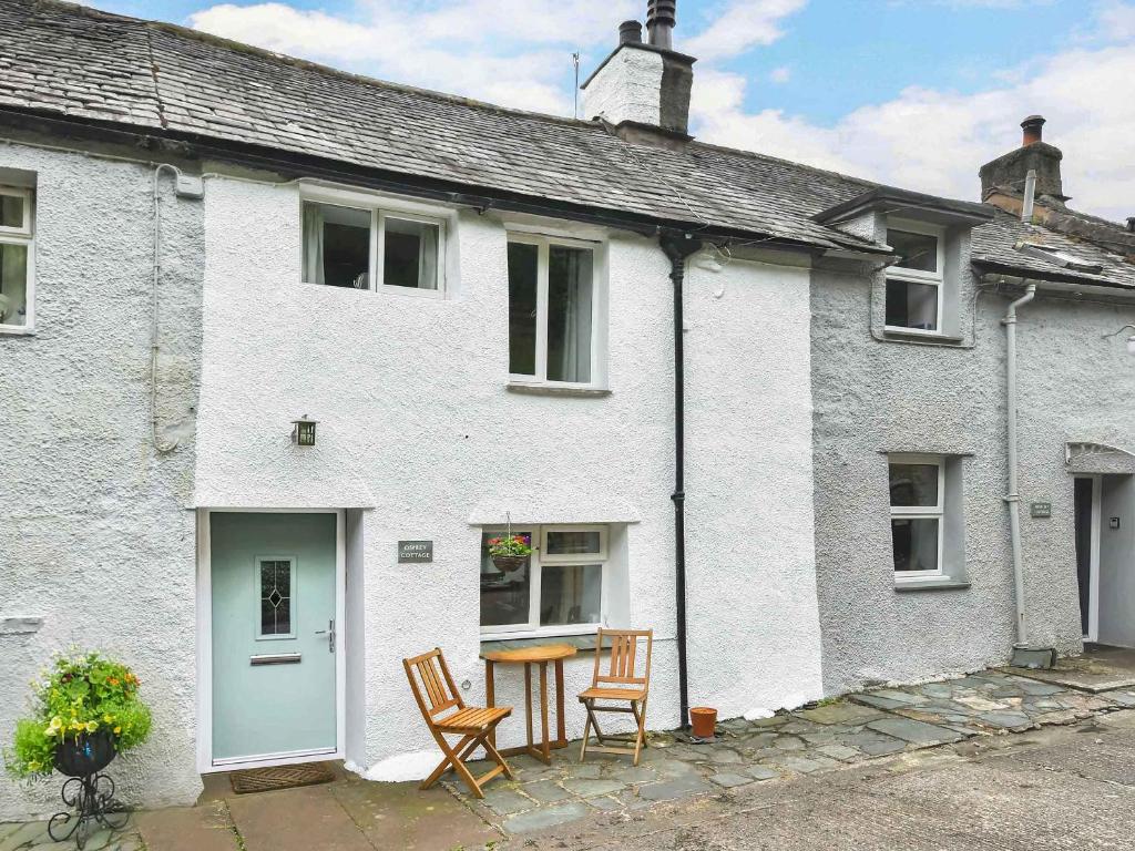 a white house with two chairs and a table at Osprey Cottage in Bassenthwaite
