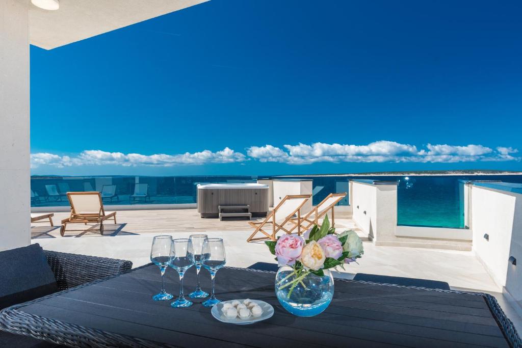 a table with wine glasses and a vase with flowers at Luxury Mandre Penthouse in Mandre