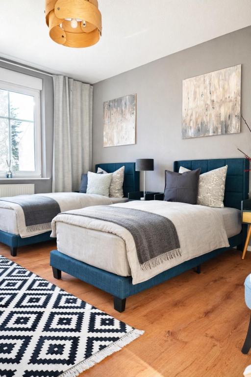 two beds in a bedroom with a blue wall at Haus Gitta - Wohlfühlen & Genießen in Luckenwalde