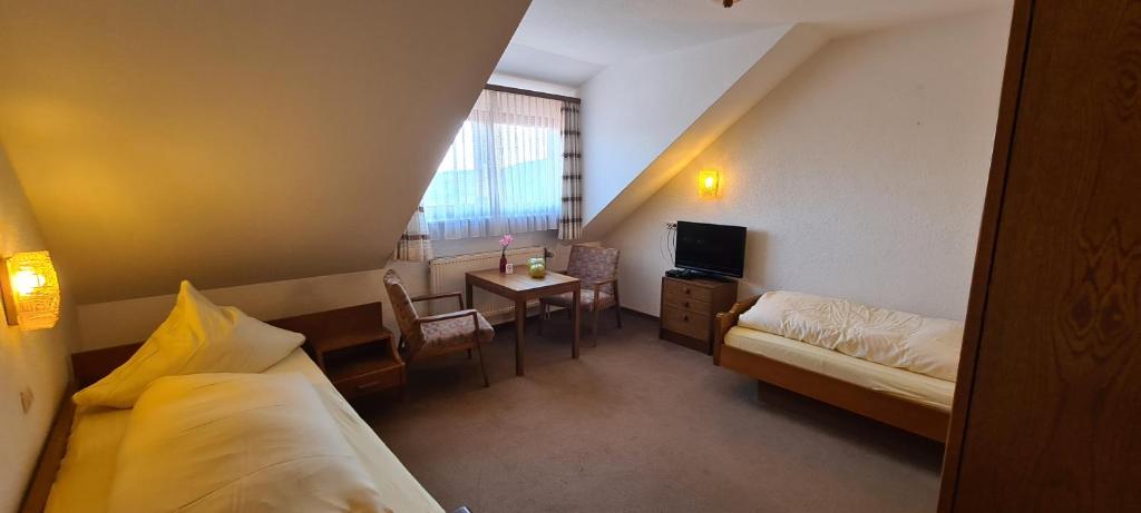 a hotel room with a bed and a desk and a bed and a table at Pension Hauber - Hotzenwaldblick in Herrischried