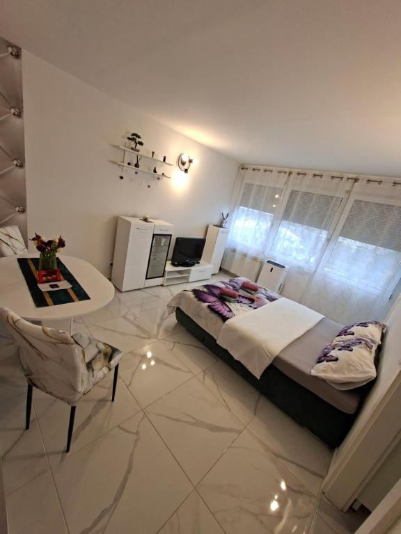 a bedroom with a large bed and a table and chair at Studio apartman Franka in Vukovar