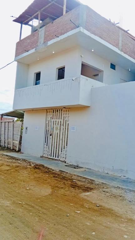 a white building with a gate in front of it at Casa Excalibur in Máncora