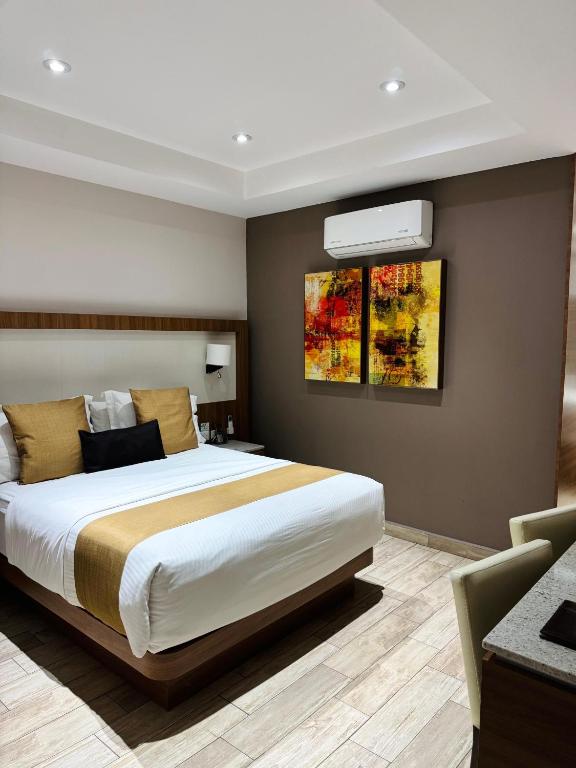 ein Schlafzimmer mit einem Bett und einem Gemälde an der Wand in der Unterkunft Hotel Soleil Business Class in León