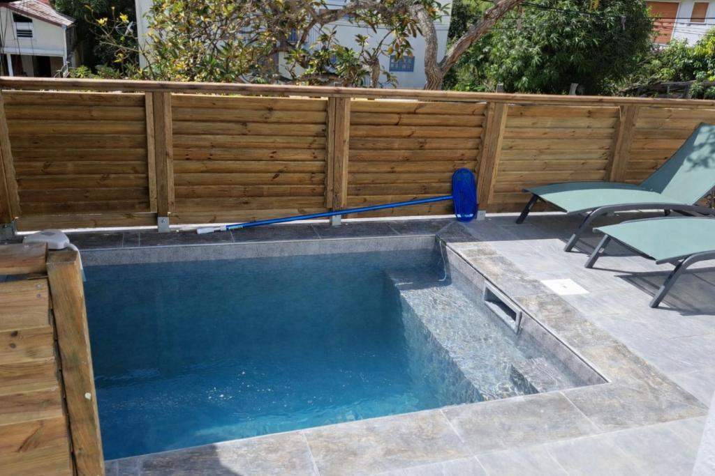 a swimming pool with two lawn chairs and a swimming poolmop at Ti Zeinga La T2 avec piscine et spa privatifs Sainte-Anne in Sainte-Anne