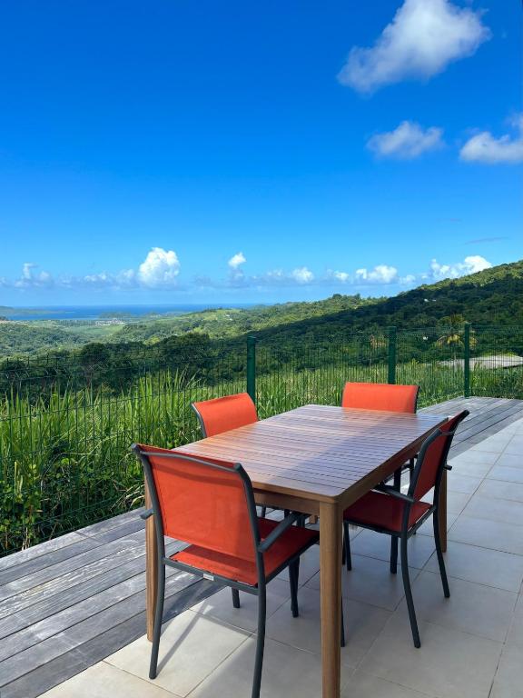 a wooden table with four chairs on a deck at Residence la Floride in Gros-Morne