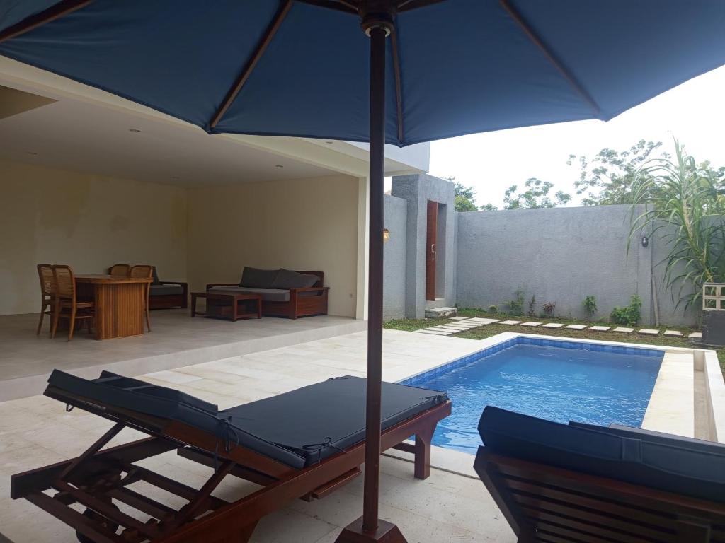 a blue umbrella sitting next to a swimming pool at villa reyray in Jimbaran