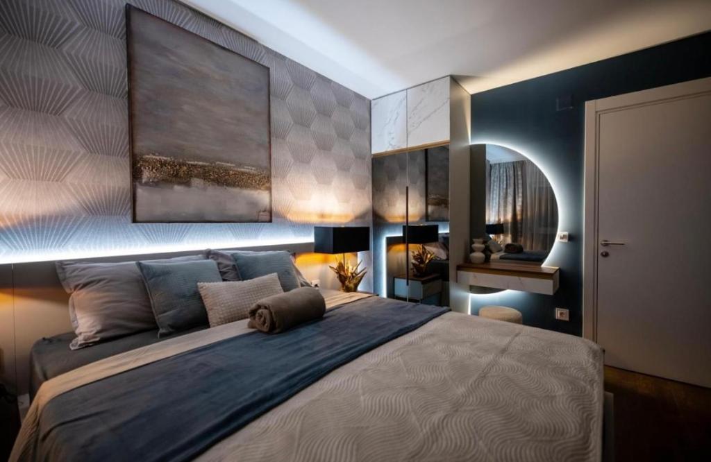 a bedroom with a large bed with a painting on the wall at Impresia apartments in Kragujevac
