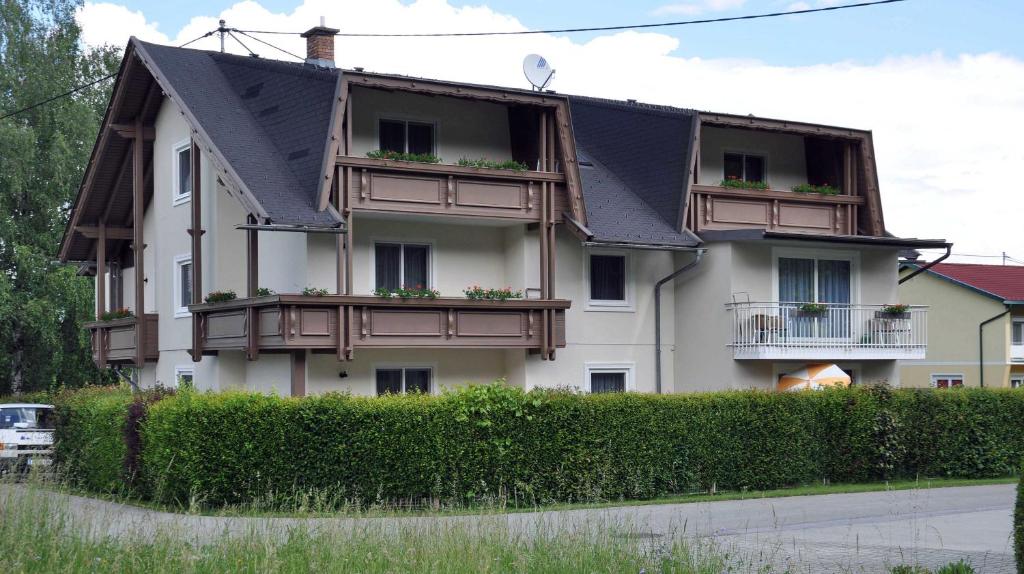 ein weißes Gebäude mit schwarzem Dach und Balkonen in der Unterkunft Appartements Irene in Sankt Kanzian am Klopeiner See
