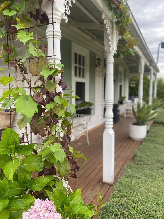 a front porch of a white house with flowers at Korumburra Farmhouse in Korumburra