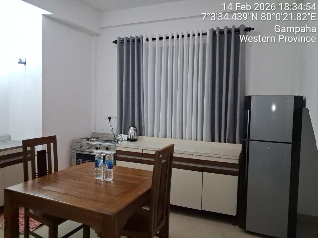 a kitchen with a wooden table and a refrigerator at Layans Properties in Gampaha