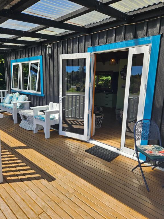 a wooden deck with a door and chairs on it at The Blackhouse Cottage in Hokitika