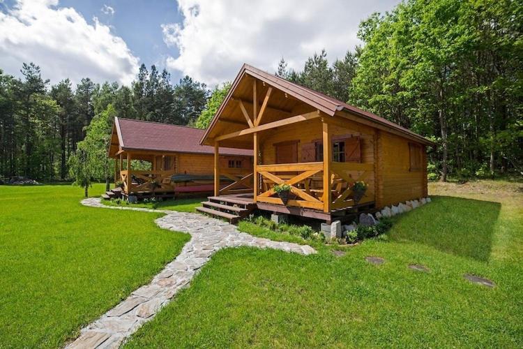 a large log cabin with a walkway leading to it at Summer cottages in Kashubia in Gostkowo