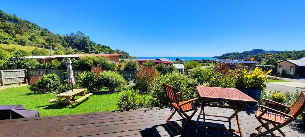 a deck with chairs and a picnic table and the ocean at Cedar Cottage in Takaka
