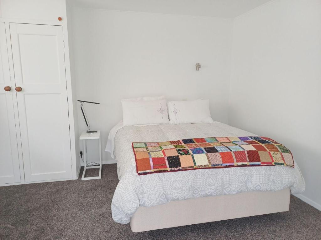 a bedroom with a bed with a quilt on it at Marigold in Manurewa in Auckland