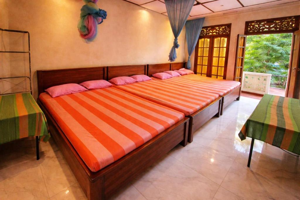a large bed with pink pillows in a room at Lavanya Holiday Resort Kataragama in Kataragama