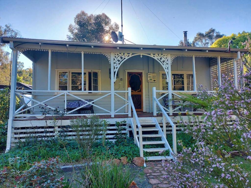 a yellow house with a porch and a staircase at Forest Edge Cottage Dwellingup in Dwellingup