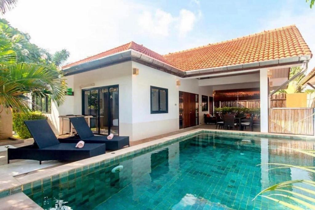 a villa with a swimming pool and a house at Malee Beach C6 in Phra Ae beach