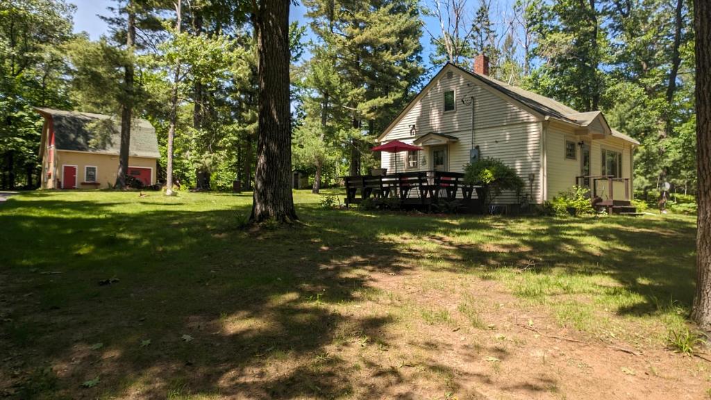 a house in the middle of a yard with trees at Yellow Barn House in Danbury